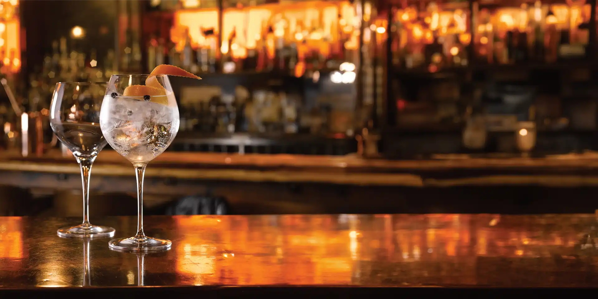 image of two gin glasses on a warm autumn shaded bar top