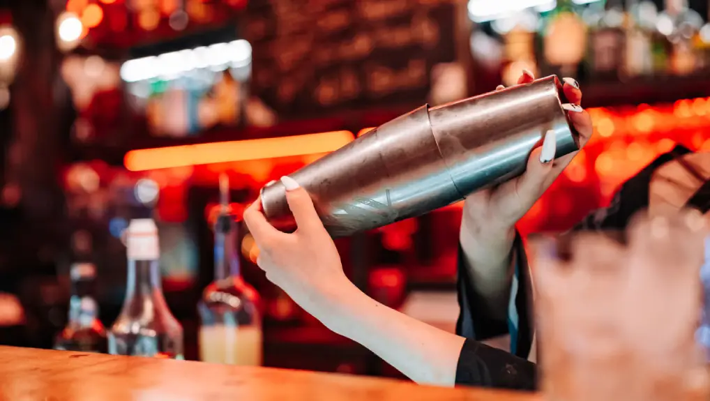 Close up image looking at the types of cocktail shaker image of a Boston cocktail shaker in a bar setting.