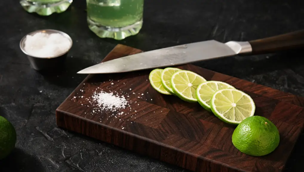 close up image of a cutting board and knife part of the essential bar tools required in a bar setting.