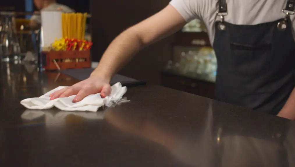 image of a bartender cleaning and sanitising a bar