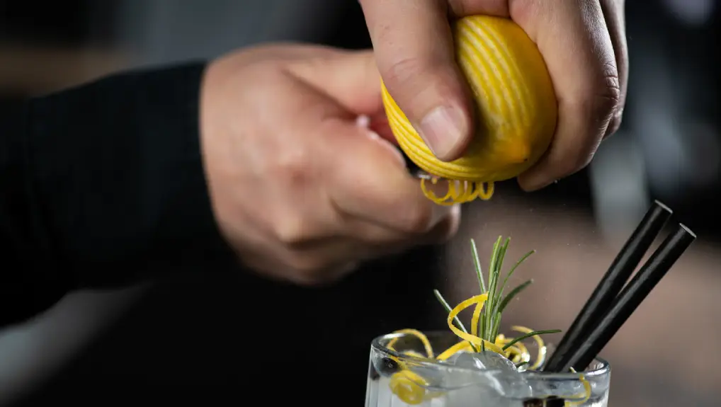 close up image of a bartender cutting and garnishing a cocktail