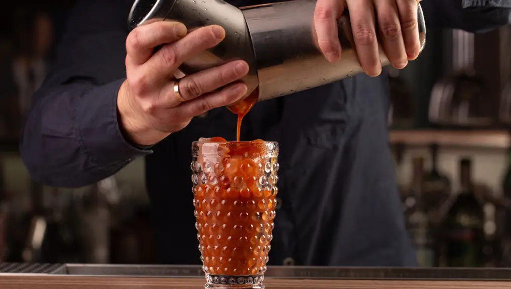 Close up image of a bartender using a eco-friendly bar tools and equipment including a cocktail shaker