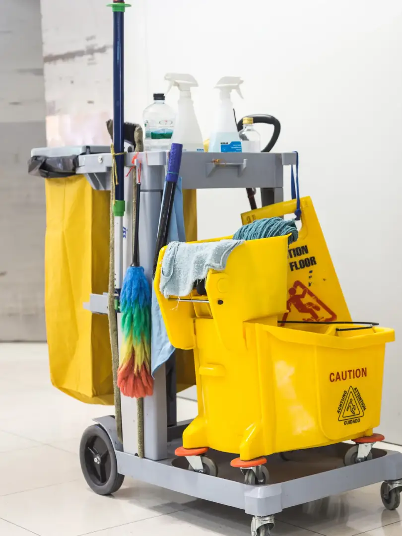 Image of cleaning supplies stacked on a yellow  and grey trolley