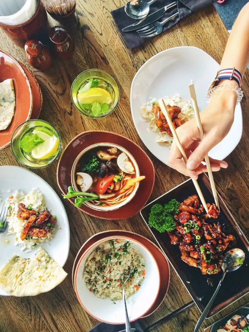 Image of a table top packed with various dishes of food in a front-of-house restaurant 