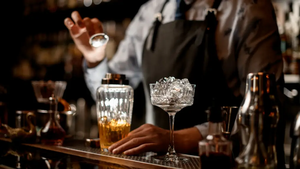 Close up image of a bartender using essential bar tools to make a cocktail