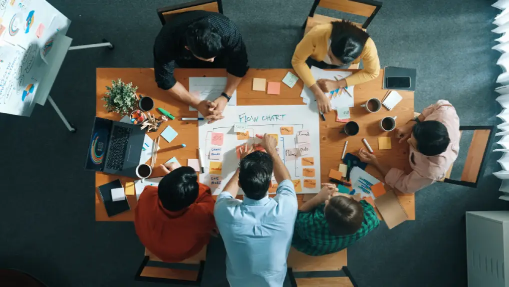 Image of a business meeting taken from above in plan view the image represents a meeting setting up a business structure