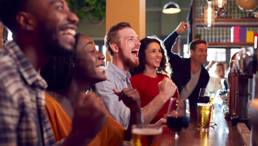 Image of a busy local bar with people laughing and smiling and enjoying the moment.