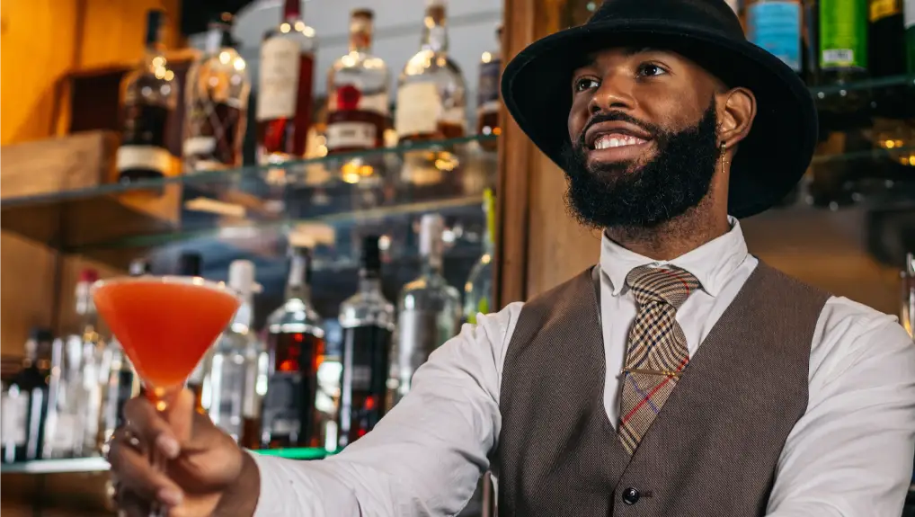 Image of bartender serving a red cocktail in a bright bar