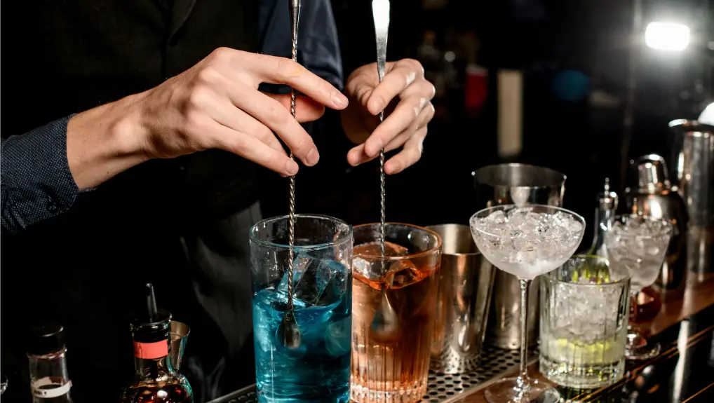 image of a bar serving cocktails using bar spoons and other historical inspired bar tools